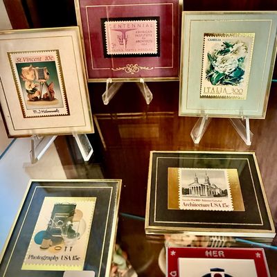 Sale Photo Thumbnail #114: Collection of five framed vintage postage stamps, including US and international issues, displayed on individual acrylic stands.