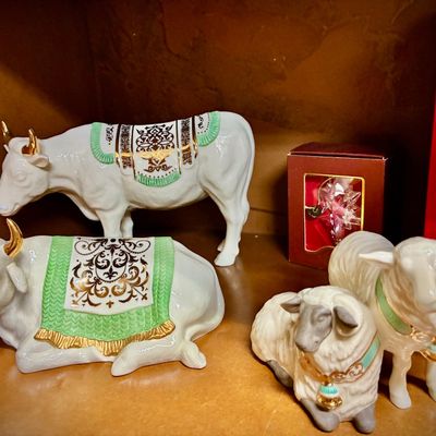 Sale Photo Thumbnail #127: Lenox porcelain nativity animals, including standing and reclining cows with green and gold blankets, alongside two sheep figurines.