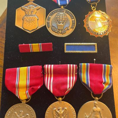 Sale Photo Thumbnail #85: Collection of United States military service medals and ribbons, including a National Defense Service Medal, an Army Good Conduct Medal, and a World War II Victory Medal, displayed on a black velvet board.