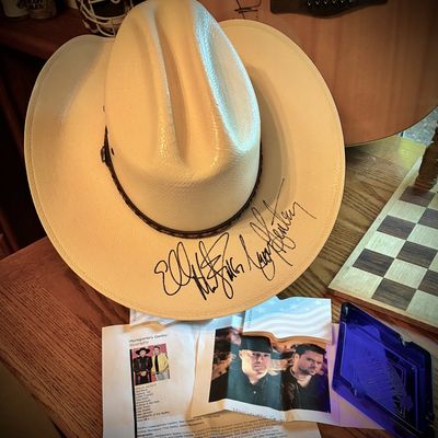 Sale Photo Thumbnail #190: Autographed Montgomery Gentry straw cowboy hat, signed on the brim by Eddie Montgomery and Troy Gentry, displayed with band biography materials.
