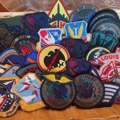 Sale Photo Thumbnail #247: Collection of vintage military and civil engineering embroidered patches, including USAF Civil Engineering and Strategic Air Command designs, displayed in a wicker basket.