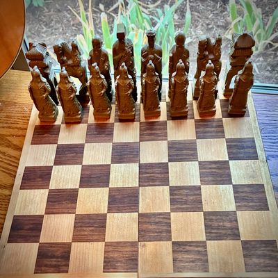 Sale Photo Thumbnail #209: Vintage Asian-themed chess set featuring carved resin or composite pieces on a folding wooden chessboard.