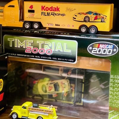 Sale Photo Thumbnail #229: NASCAR 2000 Time Trial 1:64 scale transporter set featuring Kodak Film Racing, alongside a yellow U.S. Army Air Force toy fire truck.