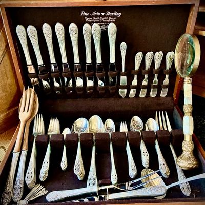 Sale Photo Thumbnail #250: Fine Arts Sterling silver flatware set in a wooden storage chest, featuring ornate handles and including various serving utensils.