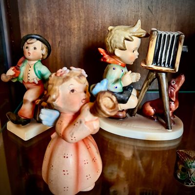 Sale Photo Thumbnail #67: Collection of vintage Goebel Hummel figurines, including a boy with a camera and dog, a boy playing a horn, and a small angel playing a horn.