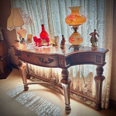Sale Photo Thumbnail #57: Traditional wooden demi-lune console table with carved legs, displaying vintage lamps, red glassware, and decorative figurines.