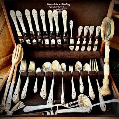 Sale Photo Thumbnail #6: Sterling silver flatware set in a vintage wooden storage chest, featuring ornate handles and including serving utensils and a decorative magnifying glass.
