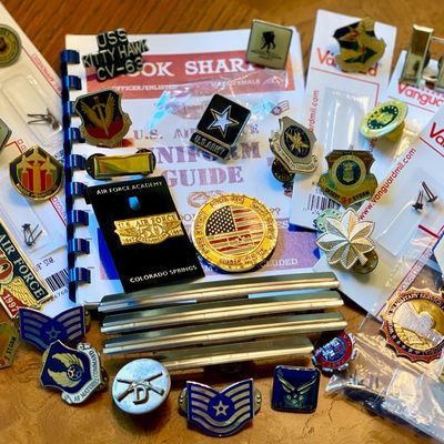 Sale Photo Thumbnail #248: Collection of United States Air Force and military memorabilia, including pins, medals, rank insignia, and a uniform guide booklet.