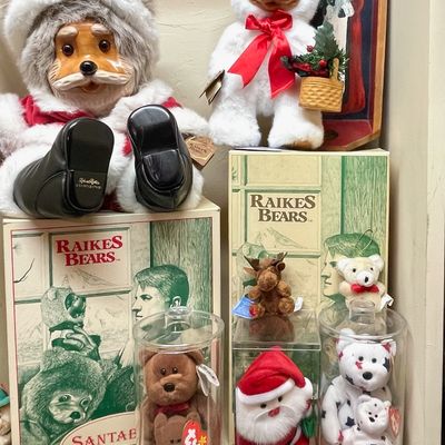 Sale Photo Thumbnail #160: Collection of vintage Raikes Bears with carved wooden faces, including a large Santa bear, alongside various Ty Beanie Babies in protective display cases.
