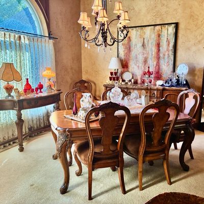Sale Photo Thumbnail #31: Traditional formal dining room set featuring a carved wood extension table with matching high-back chairs, a console table, a buffet, and a glass display cabinet.