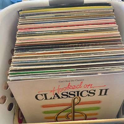 Sale Photo Thumbnail #132: A collection of vintage vinyl LP records stored in a white plastic laundry basket, featuring "Hooked on Classics II" at the front.