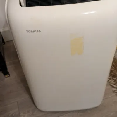 Sale Photo Thumbnail #28: Toshiba portable air conditioner in a white plastic housing, showing some adhesive residue on the front panel.