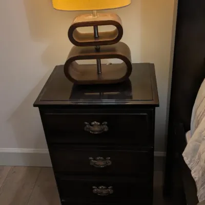 Sale Photo Thumbnail #30: Mid-century modern style table lamp with stacked wooden oval loops on a dark wood four-drawer nightstand.