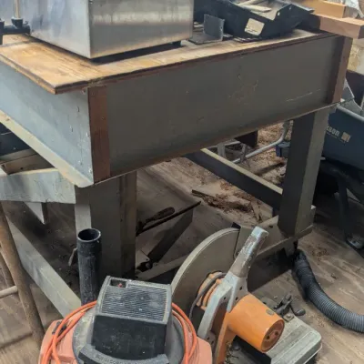 Sale Photo Thumbnail #42: Industrial workshop equipment including a heavy-duty metal workbench, a wet/dry shop vacuum with an orange power cord, and a vintage orange chop saw.