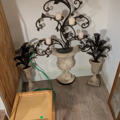 Sale Photo Thumbnail #21: Ornate wrought iron candelabra in a tree-like design, set in a distressed stone-look urn, flanked by two matching smaller urns with metal foliage.