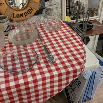 Sale Photo Thumbnail #14: Assorted vintage glassware and kitchen items, including a clear glass cookie jar, pie dish, and plates, displayed alongside a decorative Titanic London life preserver mirror.