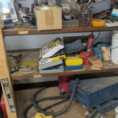 Sale Photo Thumbnail #87: Assorted workshop tools, hardware, and storage containers on wooden shelving units and the floor.