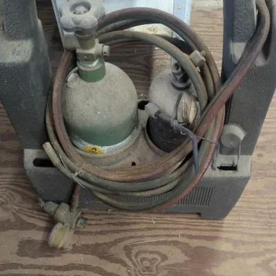 Sale Photo Thumbnail #55: Portable oxy-acetylene torch kit in a molded plastic carrying stand, showing significant dust and wear from storage.