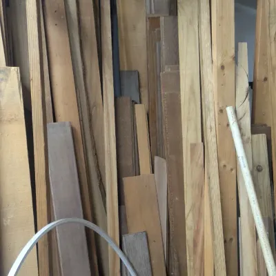 Sale Photo Thumbnail #50: Assorted scrap lumber and wooden boards of various lengths and widths stored vertically in a workshop.