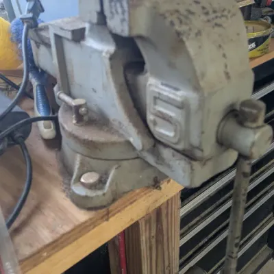 Sale Photo Thumbnail #54: Vintage heavy-duty bench vise with a swivel base, showing some surface wear and rust from use.
