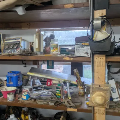Sale Photo Thumbnail #86: Wooden workshop shelving unit filled with various tools, hardware, containers, and safety equipment.