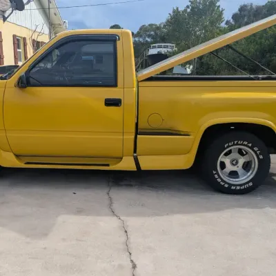 Sale Photo Thumbnail #56: Custom yellow Chevrolet C/K single-cab pickup truck with a matching hard tonneau cover and aftermarket wheels.
