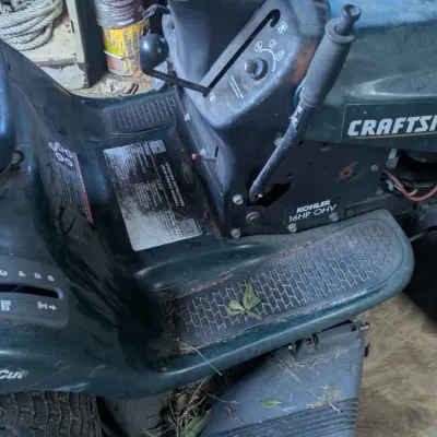 Sale Photo Thumbnail #45: Craftsman riding lawn mower featuring a 16 HP Kohler OHV engine and a 42-inch cutting deck, showing signs of use and storage.