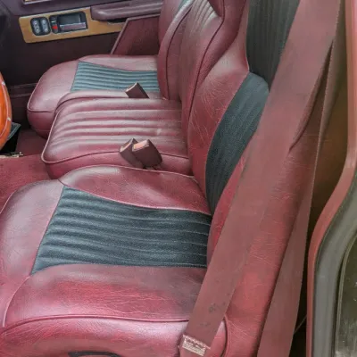 Sale Photo Thumbnail #61: Custom burgundy and black vinyl bench seat inside a vintage pickup truck, featuring woodgrain door panel accents.