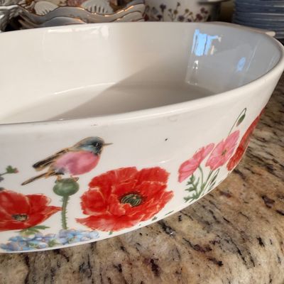 Sale Photo Thumbnail #70: White ceramic oval baking dish featuring a colorful illustration of a pink bird perched among red poppies and blue hydrangeas.