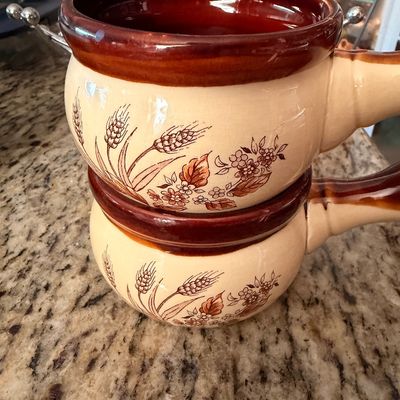 Sale Photo Thumbnail #73: Pair of vintage ceramic soup bowls with handles, featuring a brown drip glaze rim and a wheat and floral motif on a beige background.