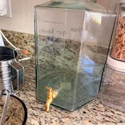 Sale Photo Thumbnail #78: Large hexagonal glass beverage dispenser with a brass-colored spigot and matching glass lid.