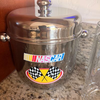 Sale Photo Thumbnail #147: Vintage NASCAR branded stainless steel ice bucket with lid and side handles, featuring the classic logo and checkered flags.