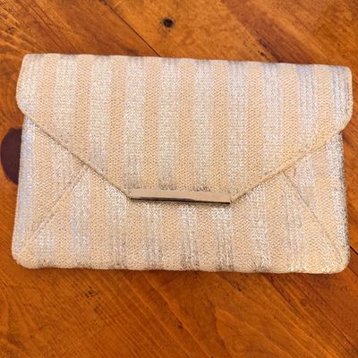 Sale Photo Thumbnail #25: Vintage envelope-style clutch purse featuring a woven metallic silver and cream striped pattern with a silver-tone metal bar accent on the front flap.