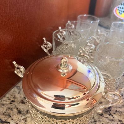 Sale Photo Thumbnail #145: Vintage silver-plated and glass condiment set, featuring a lidded sugar bowl and matching small glasses in ornate filigree holders.