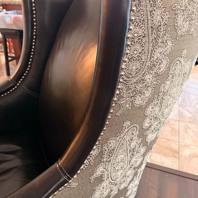 Sale Photo Thumbnail #12: Traditional wingback armchair featuring dark brown leather upholstery on the interior, a grey and white paisley fabric exterior, and silver nailhead trim.