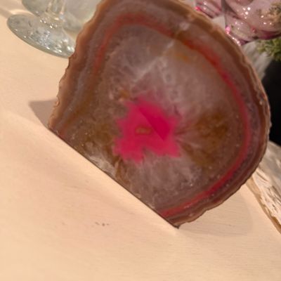 Sale Photo Thumbnail #122: Polished agate slice with a dyed pink center, standing upright on a flat edge.
