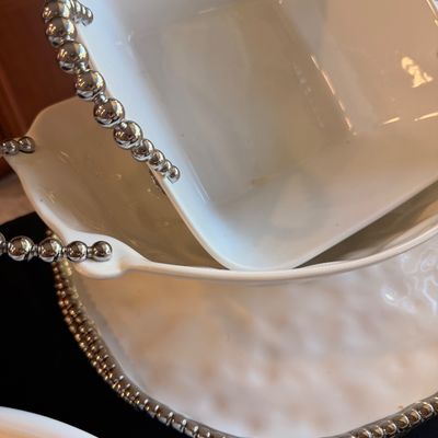 Sale Photo Thumbnail #132: Beatriz Ball white melamine serving pieces featuring signature metallic beaded trim, including a square bowl and a larger textured platter.