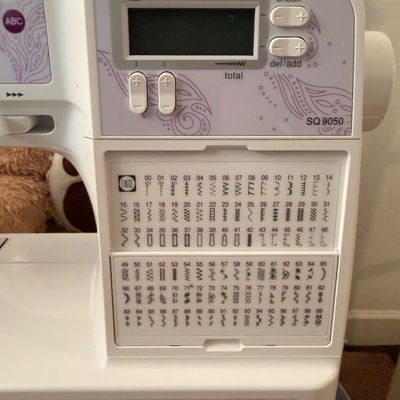 Sale Photo Thumbnail #8: Brother SQ9050 computerized sewing and quilting machine, featuring a digital display screen and a comprehensive stitch selection guide.