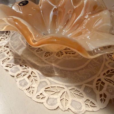 Sale Photo Thumbnail #57: Vintage peach opalescent art glass bowl with a ruffled edge, resting on a white lace doily.