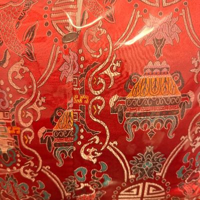 Sale Photo Thumbnail #117: Red silk brocade pillow cover featuring traditional Chinese motifs, including Shou characters, lotus flowers, and incense burners, sealed in protective plastic packaging.