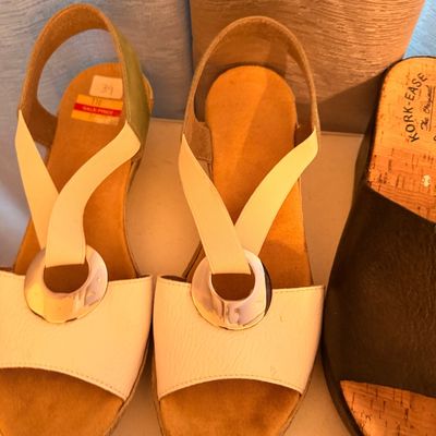 Sale Photo Thumbnail #33: Pair of white and tan wedge sandals featuring a silver-tone ring accent and elasticized straps, shown alongside a black Kork-Ease slide sandal.