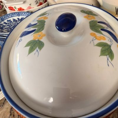 Sale Photo Thumbnail #71: Vintage ceramic covered casserole dish featuring a blue rim, a blue knob, and a hand-painted yellow floral and green leaf motif.