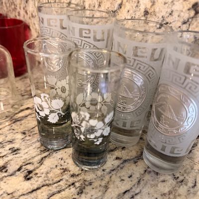 Sale Photo Thumbnail #152: Assorted vintage souvenir shot glasses, including frosted glasses featuring Cancun and Mayan pyramid motifs alongside clear glasses with white floral designs.
