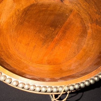 Sale Photo Thumbnail #17: Large wooden serving bowl featuring a warm finish and a decorative metal beaded rim.