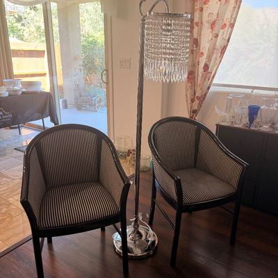 Sale Photo Thumbnail #86: Pair of modern barrel-back armchairs with black and white striped upholstery, flanking a contemporary chrome floor lamp featuring a tiered crystal bead shade.