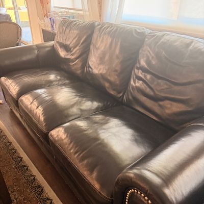 Sale Photo Thumbnail #89: Dark brown leather three-cushion sofa featuring rolled arms with brass nailhead trim.