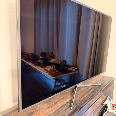 Sale Photo Thumbnail #43: Samsung flat-screen television with a silver bezel and chrome stand, resting on a rustic wooden media console.