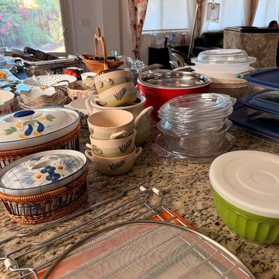 Sale Photo Thumbnail #9: Assorted kitchenware and serving dishes, including ceramic casseroles with woven baskets, stacked bowls with leaf motifs, glass storage containers, and a metal cooling rack.