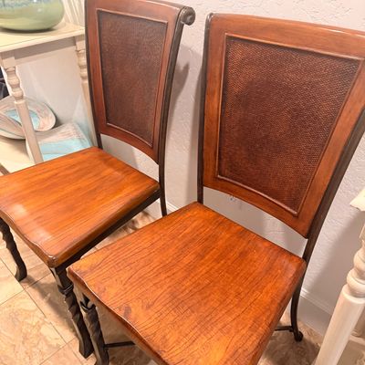 Sale Photo Thumbnail #125: Pair of contemporary dining chairs featuring warm wood seats, woven rattan back panels, and dark metal frames with twisted front legs.