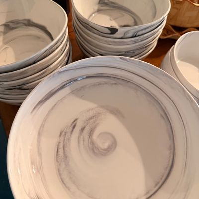 Sale Photo Thumbnail #18: Stacks of contemporary ceramic bowls featuring a white and grey marbleized swirl pattern.